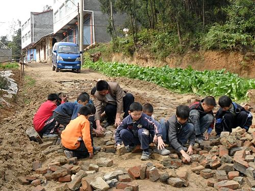 百米泥泞路 学生用肉手运石填补